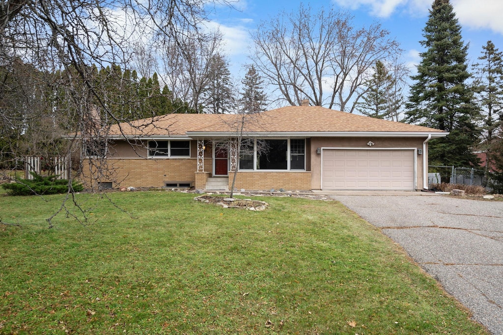 single story home with a garage and a front lawn