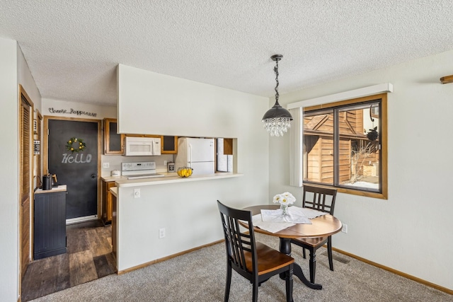 dining space featuring an inviting chandelier, a textured ceiling, and dark carpet