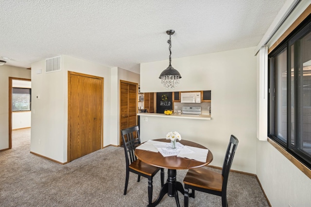 carpeted dining room with a notable chandelier and a textured ceiling