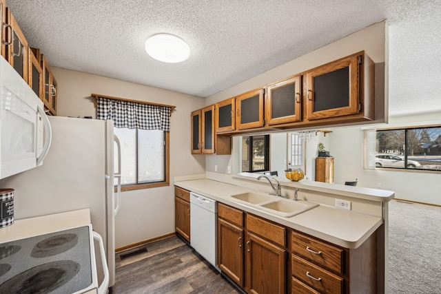 kitchen with white appliances, plenty of natural light, kitchen peninsula, and sink