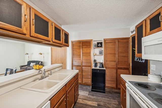 kitchen with sink, white appliances, dark wood-type flooring, and a textured ceiling