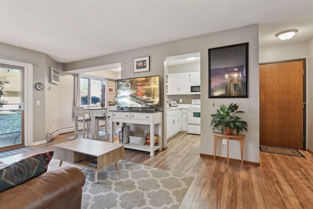 living room featuring a wall mounted AC, light hardwood / wood-style flooring, and a textured ceiling