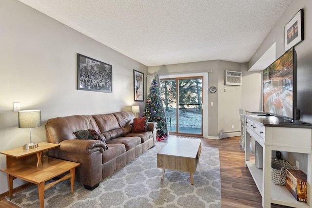 living room featuring a baseboard heating unit, a wall unit AC, hardwood / wood-style floors, and a textured ceiling