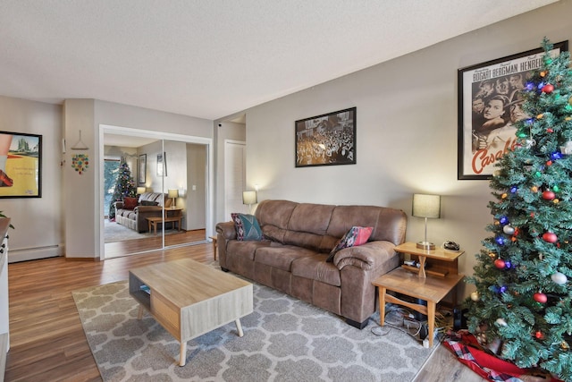 living room with hardwood / wood-style flooring, baseboard heating, and a textured ceiling