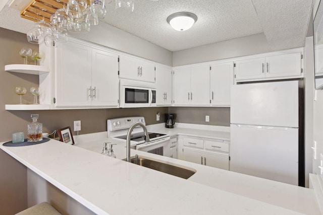 kitchen with white cabinetry, white appliances, and kitchen peninsula