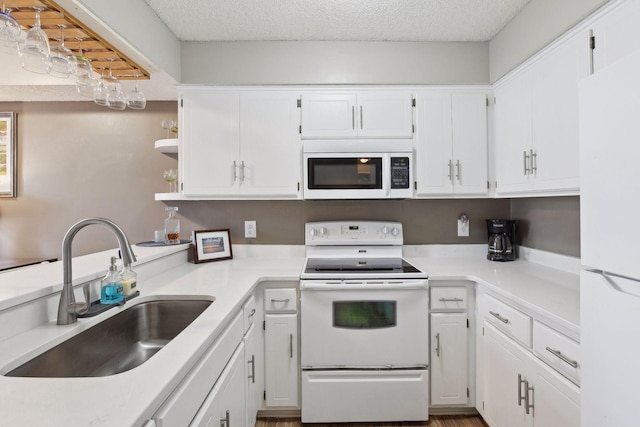 kitchen with white cabinetry, sink, white appliances, and a textured ceiling