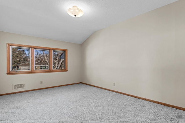 spare room featuring vaulted ceiling and light carpet