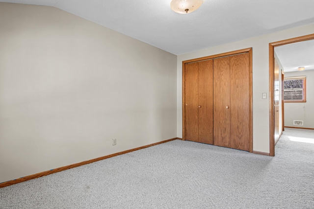 unfurnished bedroom with light carpet, vaulted ceiling, and a closet