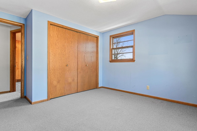 unfurnished bedroom with a closet, vaulted ceiling, and light carpet