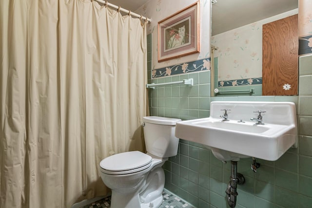 bathroom featuring sink, tile walls, and toilet