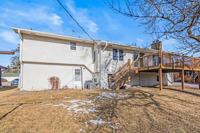 back of property with a wooden deck, cooling unit, and a lawn