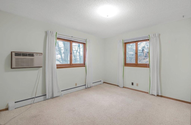 spare room with a textured ceiling, light colored carpet, and a wall mounted air conditioner