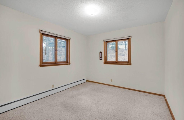 carpeted spare room with a textured ceiling, a wealth of natural light, and a baseboard heating unit