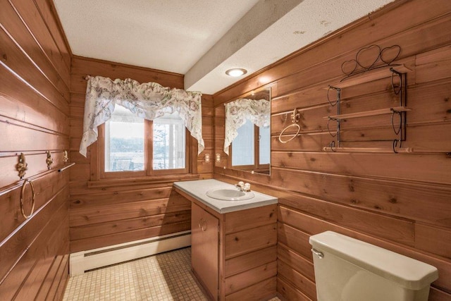 bathroom featuring vanity, wood walls, toilet, a textured ceiling, and baseboard heating