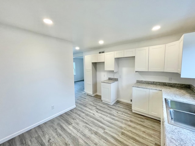 kitchen featuring light wood-type flooring, white cabinetry, and sink