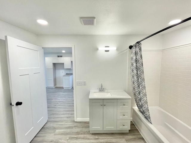 bathroom with hardwood / wood-style floors, vanity, and shower / bath combo