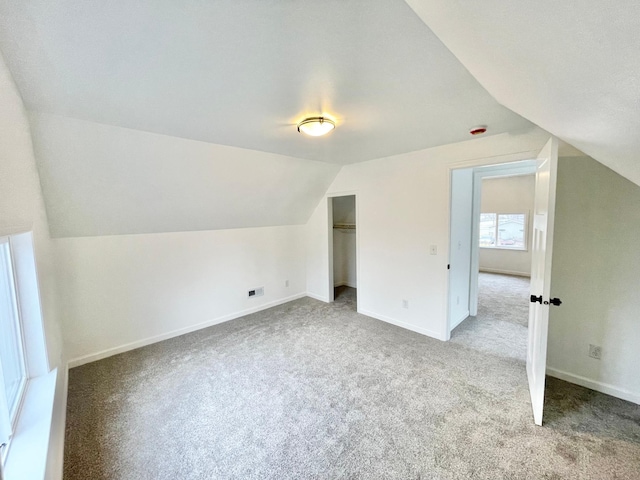 additional living space featuring light colored carpet and vaulted ceiling