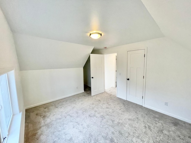 additional living space featuring light colored carpet and vaulted ceiling