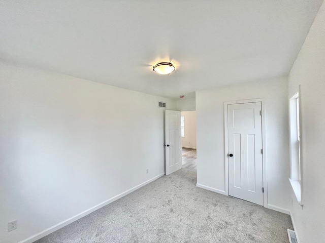 unfurnished bedroom featuring light carpet and a closet