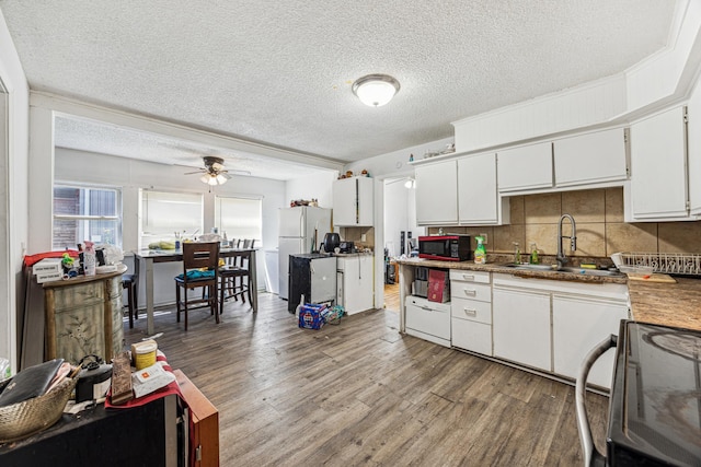 kitchen featuring sink, stainless steel range oven, white fridge, white cabinets, and hardwood / wood-style flooring