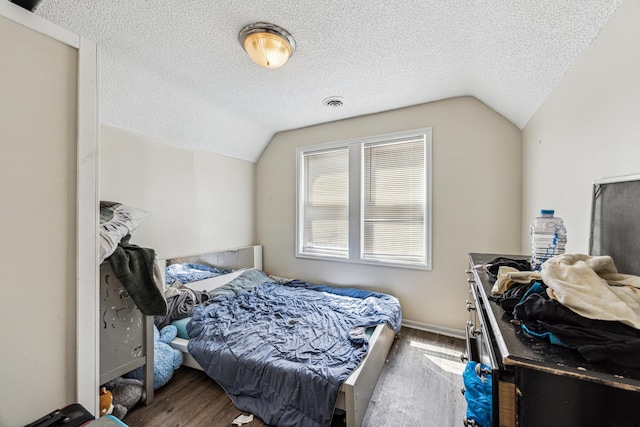 bedroom with a textured ceiling, dark hardwood / wood-style floors, and vaulted ceiling