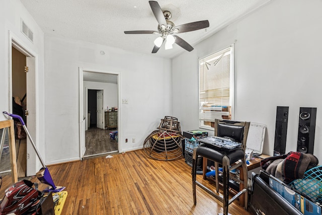 misc room with hardwood / wood-style flooring, ceiling fan, and a textured ceiling