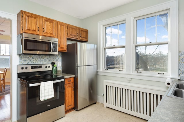 kitchen with sink, appliances with stainless steel finishes, backsplash, and radiator heating unit