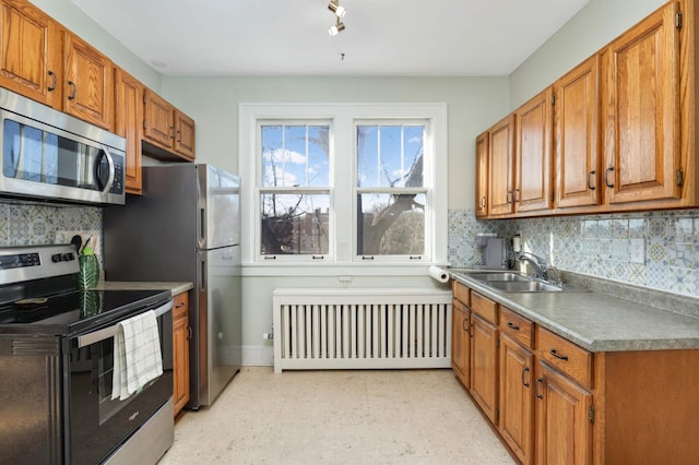 kitchen with tasteful backsplash, radiator, sink, and stainless steel appliances