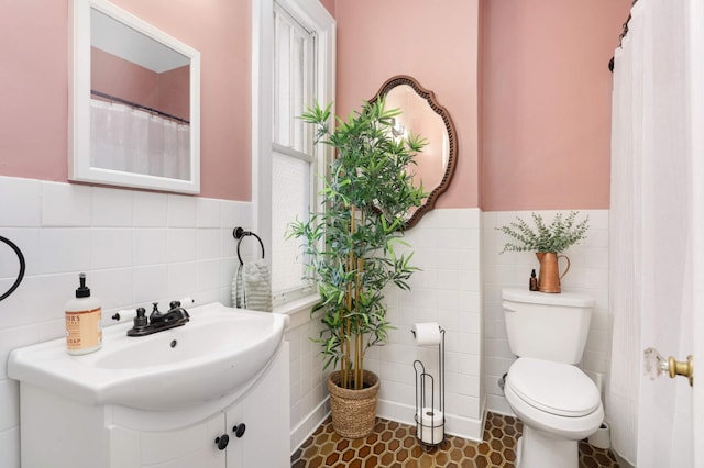 bathroom featuring tile patterned floors, toilet, and tile walls