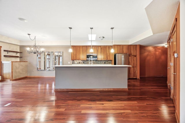 kitchen with decorative light fixtures, stainless steel appliances, and a kitchen island with sink