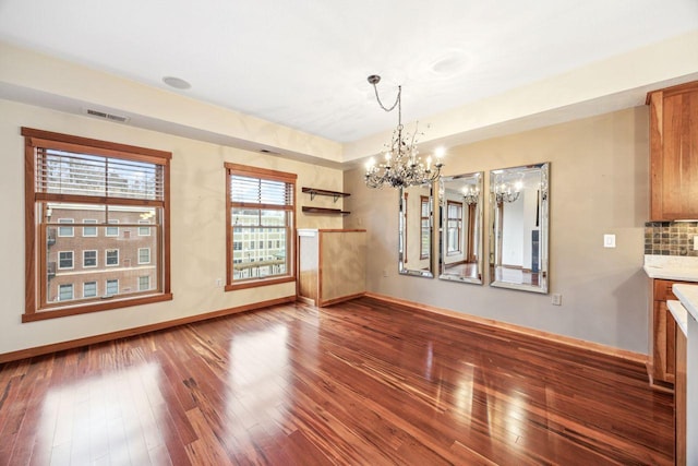 unfurnished dining area featuring a notable chandelier and wood-type flooring