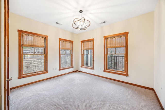 spare room featuring light carpet and an inviting chandelier