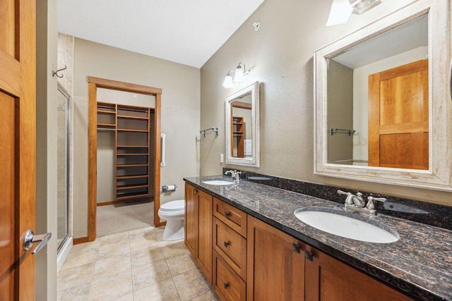 bathroom featuring tile patterned flooring, vanity, toilet, and a shower with door