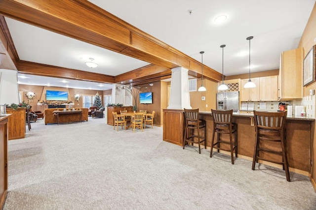 kitchen with light carpet, stainless steel refrigerator with ice dispenser, decorative backsplash, light brown cabinetry, and hanging light fixtures