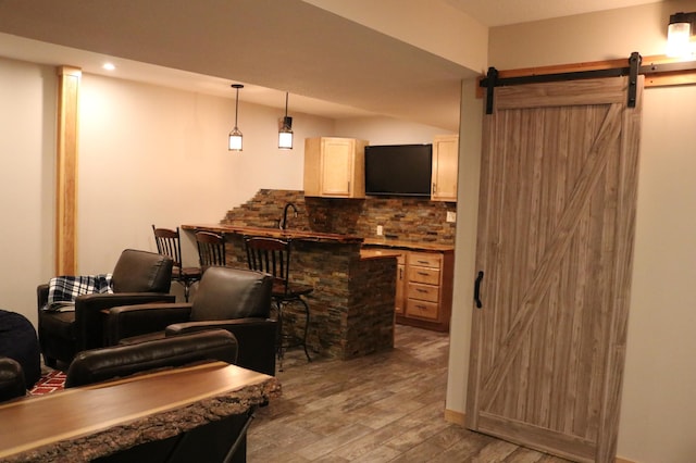 bar featuring light hardwood / wood-style flooring, a barn door, light brown cabinetry, tasteful backsplash, and decorative light fixtures