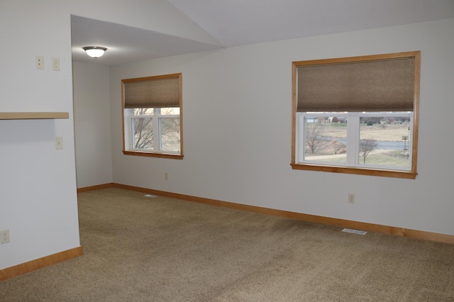 carpeted empty room with a healthy amount of sunlight and lofted ceiling