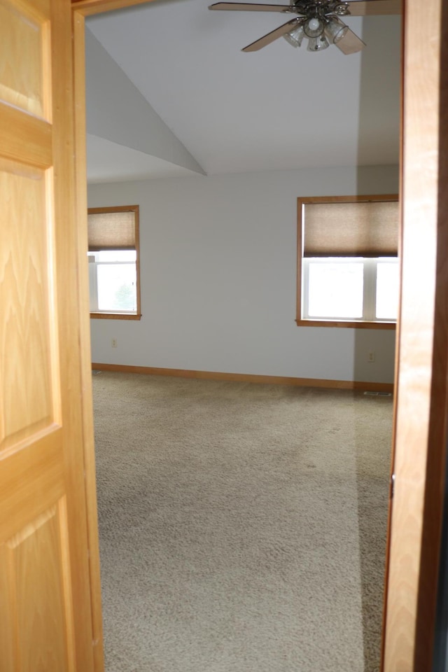 carpeted empty room with vaulted ceiling and ceiling fan