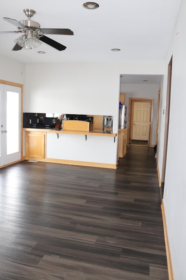 kitchen with kitchen peninsula, a breakfast bar, dark wood-type flooring, and french doors