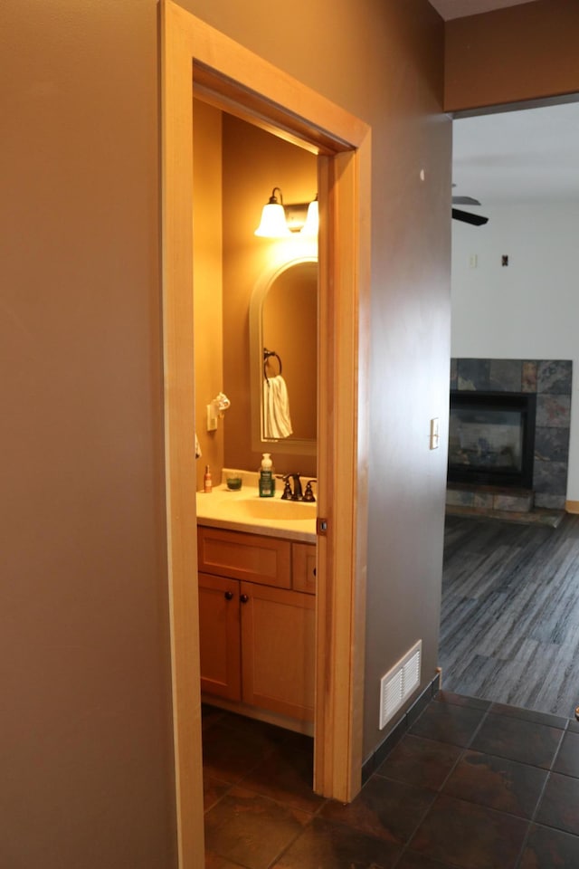 bathroom with ceiling fan, a fireplace, and vanity