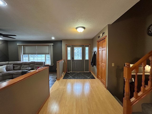 entrance foyer featuring ceiling fan, light hardwood / wood-style floors, and a textured ceiling