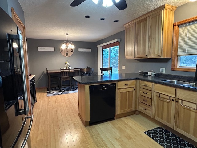 kitchen featuring kitchen peninsula, a textured ceiling, light hardwood / wood-style flooring, and black appliances