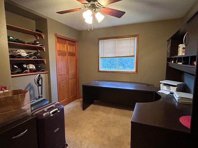 office area with a textured ceiling, light colored carpet, and ceiling fan