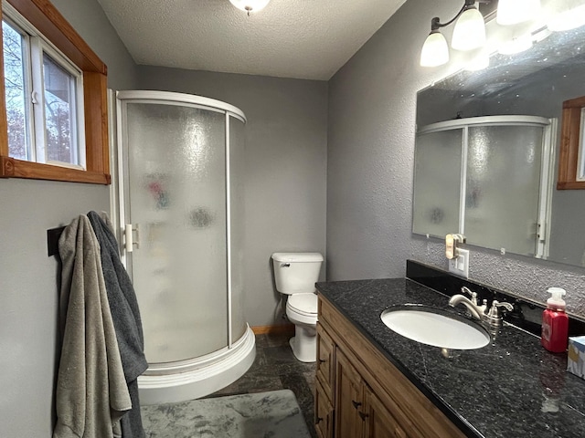 bathroom with toilet, vanity, a textured ceiling, and walk in shower