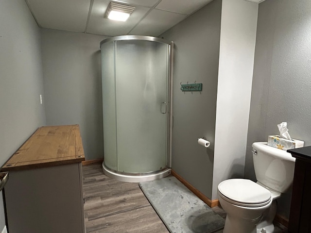 bathroom with hardwood / wood-style floors, toilet, a drop ceiling, and a shower with shower door