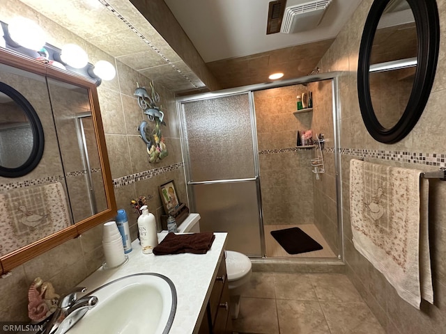 bathroom featuring tile patterned flooring, an enclosed shower, and tile walls