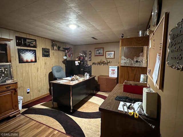 office with light wood-type flooring and wood walls