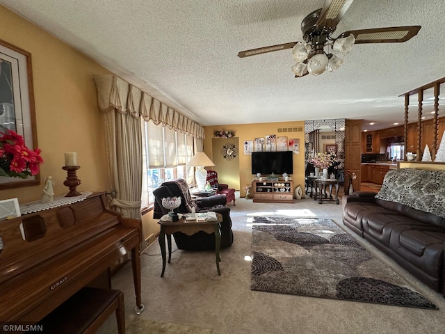 carpeted living area featuring a textured ceiling, visible vents, ornate columns, and ceiling fan