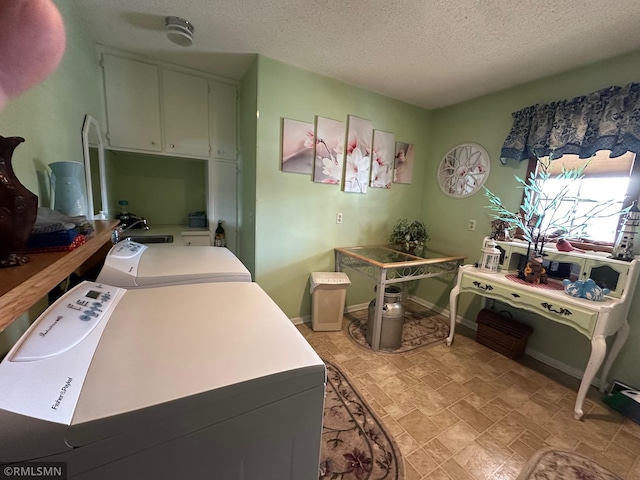 laundry room with cabinet space, stone finish floor, a textured ceiling, and separate washer and dryer