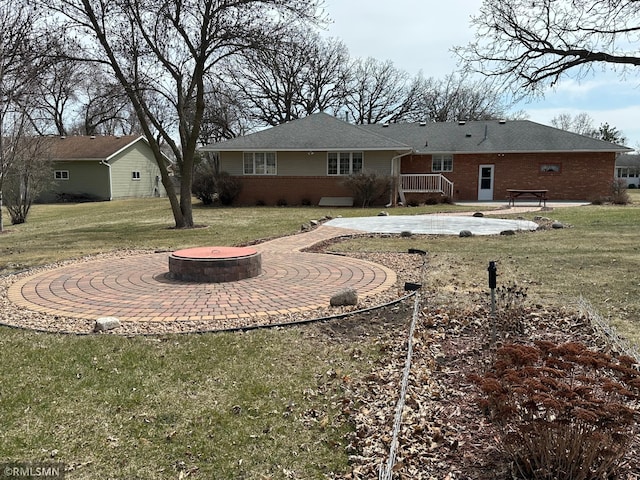 rear view of house with a patio area, brick siding, a deck, and an outdoor fire pit