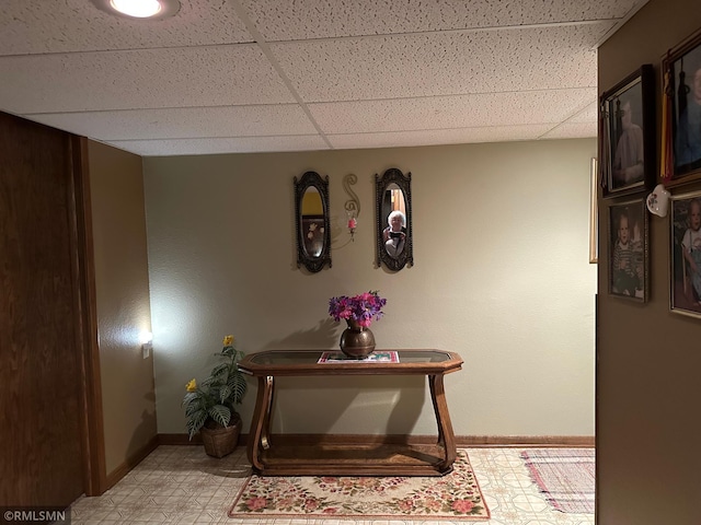 interior space with a paneled ceiling and baseboards